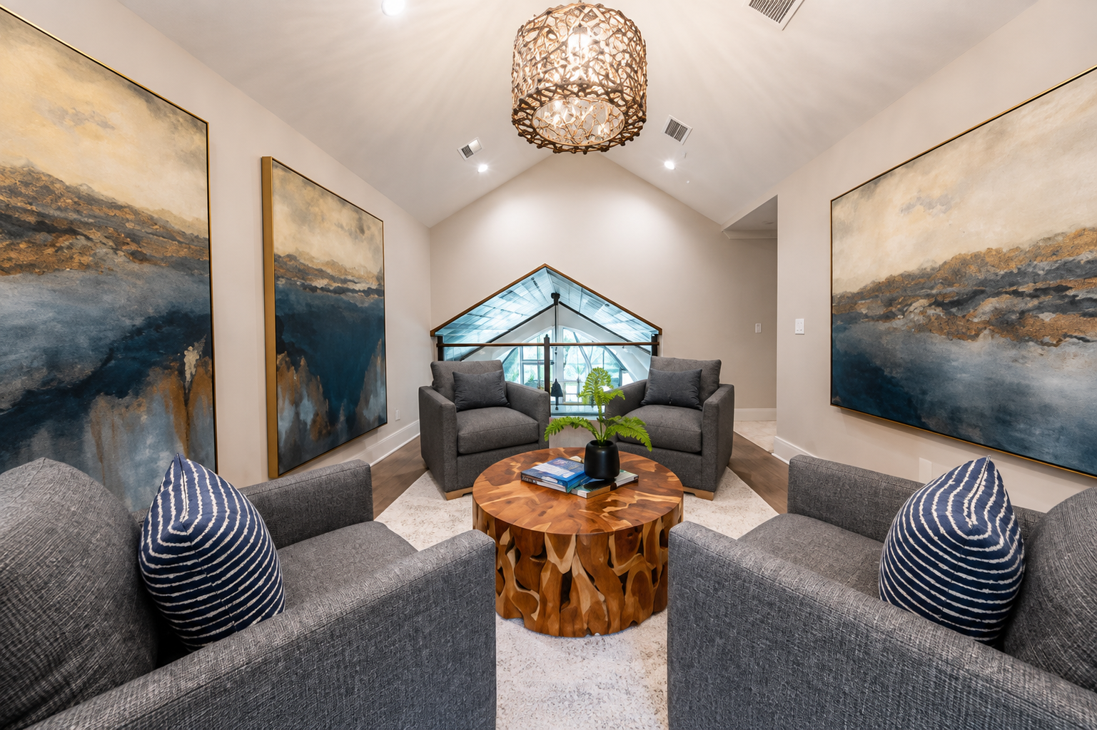 Vaulted lounge with large artwork, gray swivel chairs, and sculptural wood coffee table